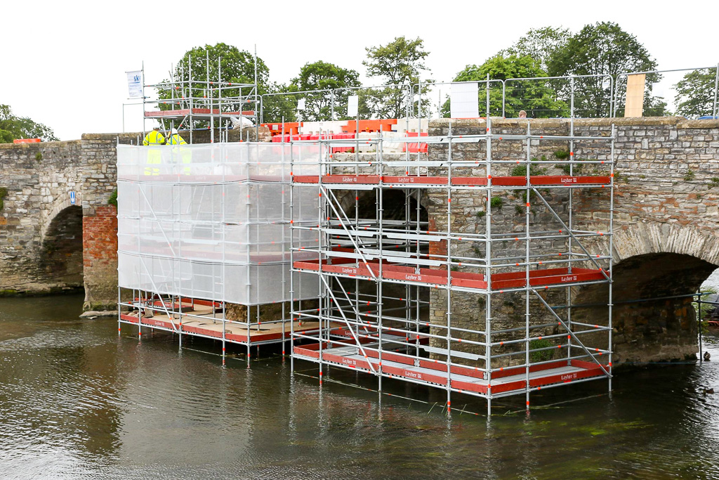 Scaffold erected from river bed providing access for repair of historic bridge