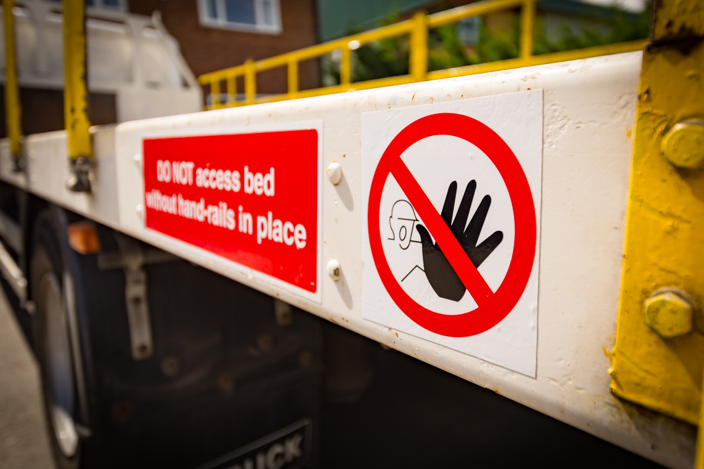 Safety sign on a scaffold truck warning no access to truck bed unless guardrails are in place