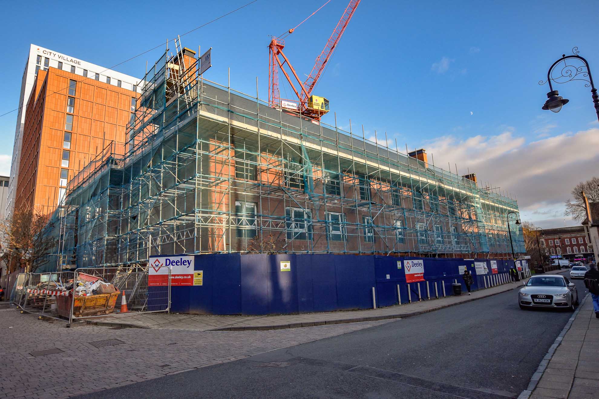 Scaffold for traditional new build care home in Coventry with blue site hoarding and crane in the background