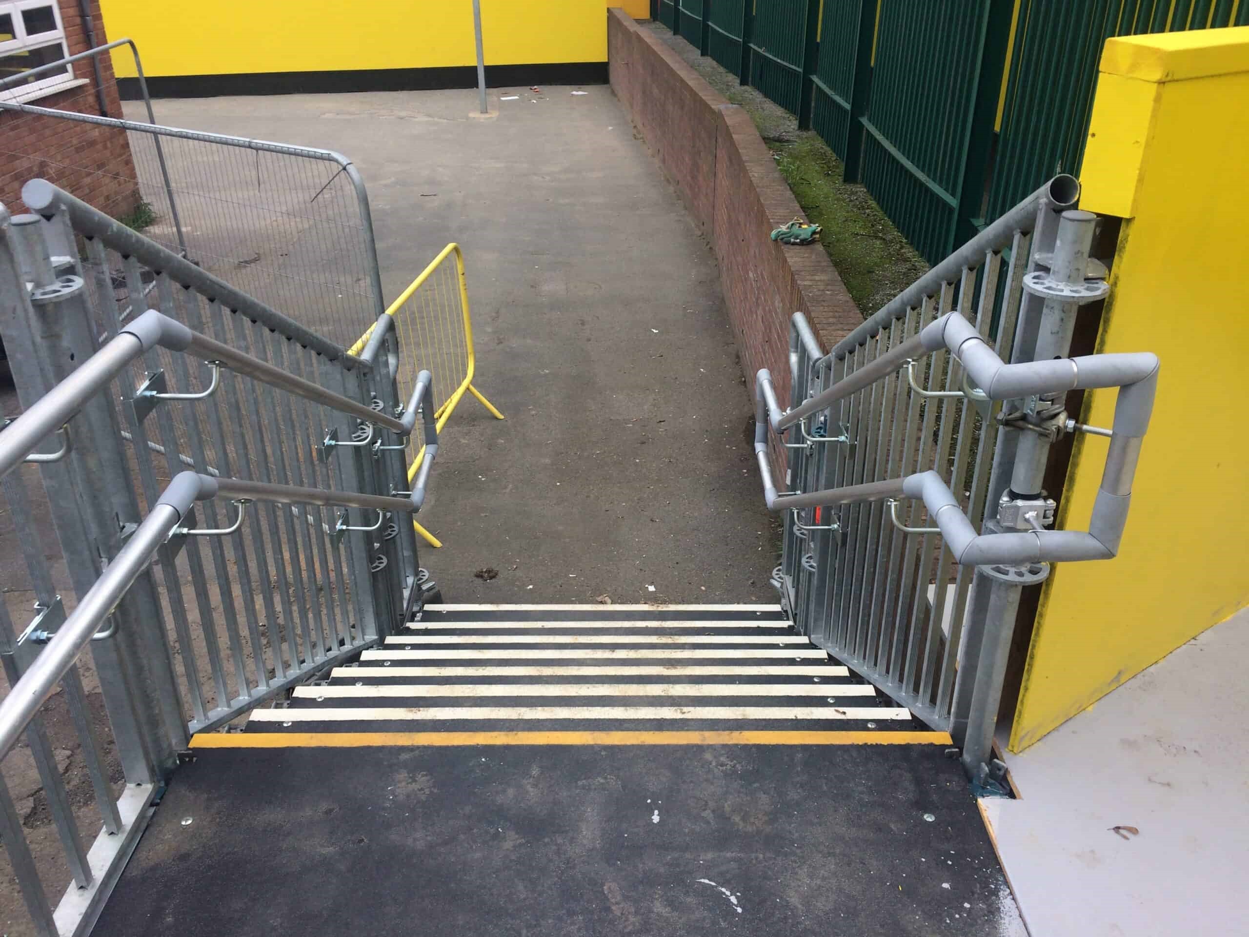 DDA compliant public access staircase constructed in Layher scaffold, with GRP flooring and double guardrails