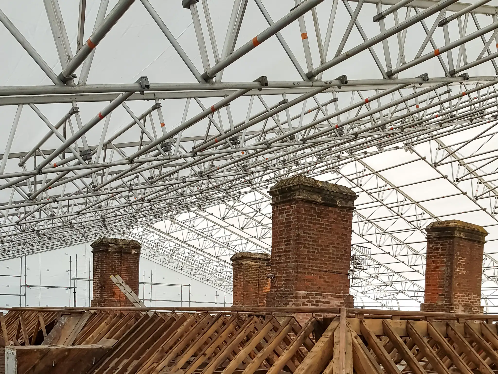 Large span duo-pitch temporary roof over brick chimneys and exposed roof timbers